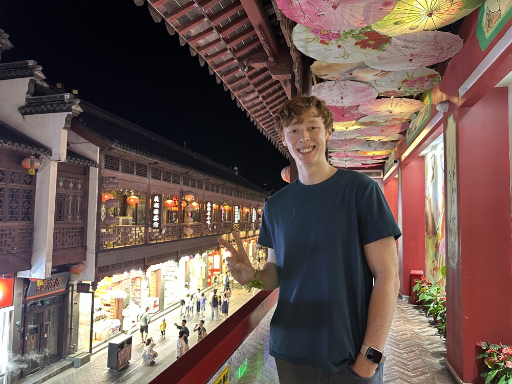 Schafer, smiling, on a balcony strung with painted paper umbrellas.
